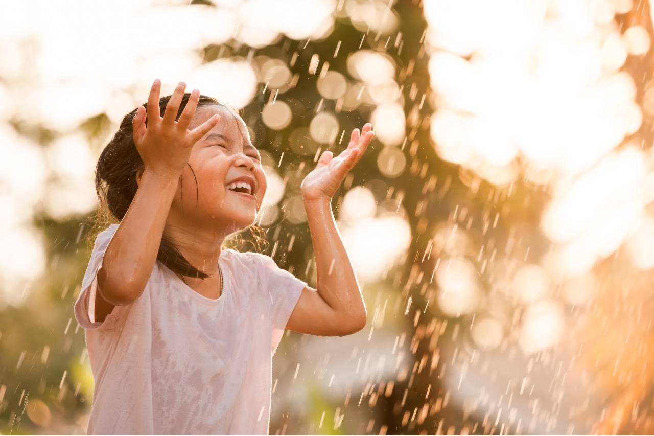 young girl playing in sprinkler