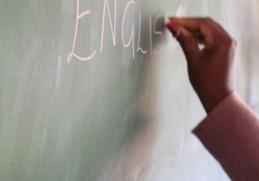 Teacher writing word English on chalkboard