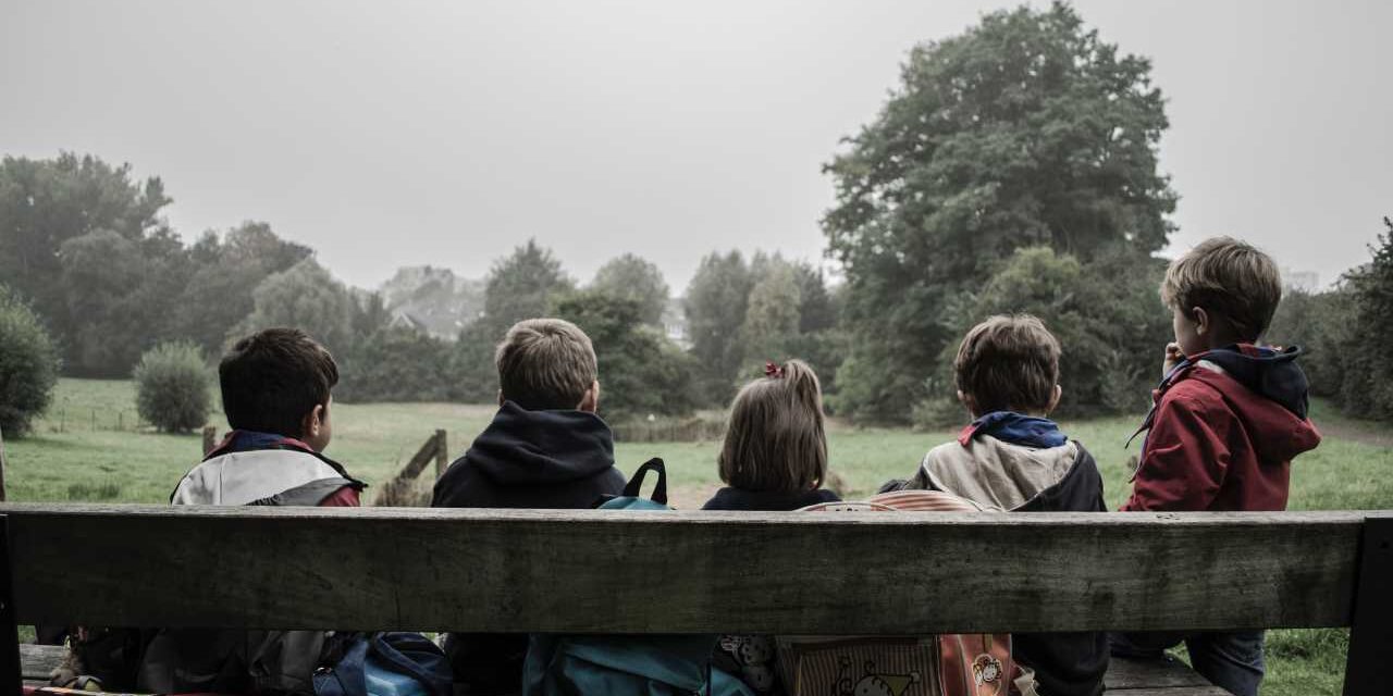 kids on a bench looking at a field